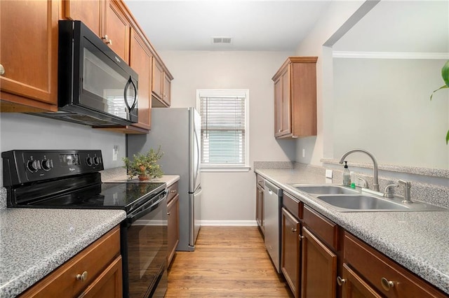 kitchen featuring black appliances, sink, light hardwood / wood-style floors, and crown molding