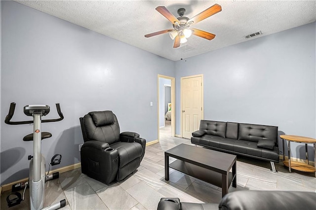 living room with a textured ceiling and ceiling fan