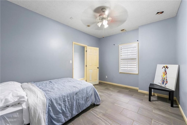 bedroom with a textured ceiling, hardwood / wood-style flooring, and ceiling fan