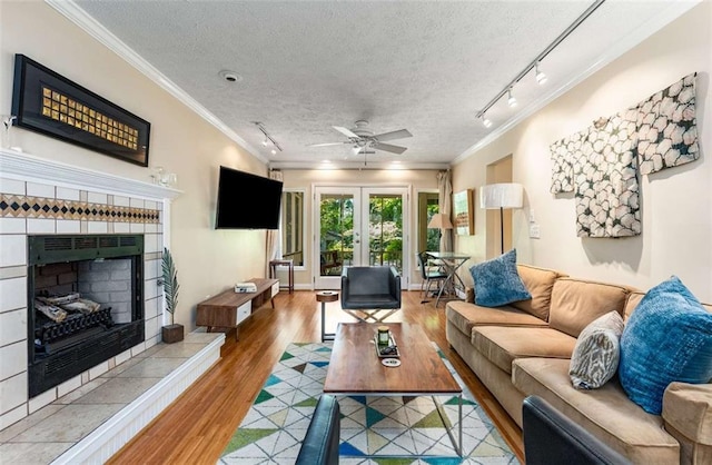 1071 Standard Dr NE, Brookhaven, GA 30319 - living room with a tiled fireplace, a textured ceiling, wood finished floors, ceiling fan, and crown molding
