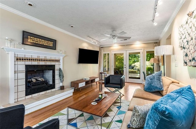 1071 Standard Dr NE, Brookhaven, GA 30319 - living area with track lighting, a tiled fireplace, light wood-type flooring, crown molding, and ceiling fan