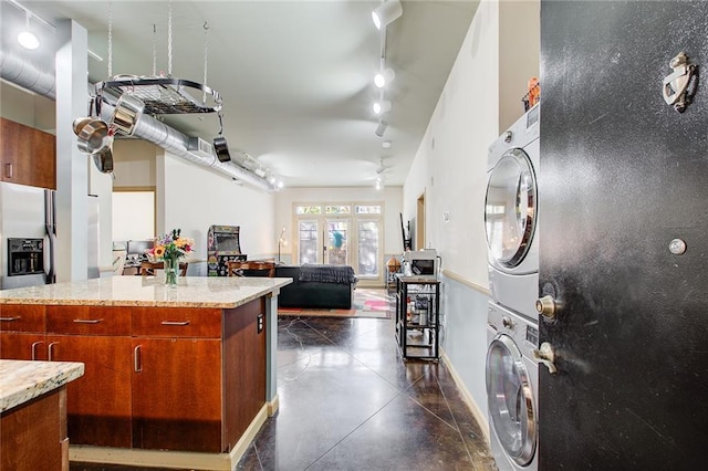 kitchen with french doors, rail lighting, stacked washer and dryer, ceiling fan, and light stone counters