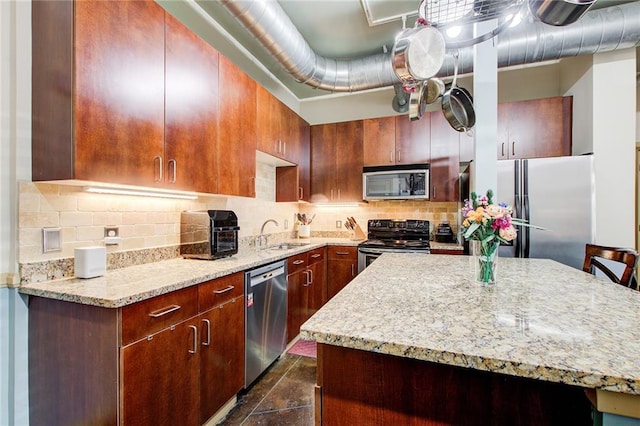 kitchen with decorative backsplash, light stone countertops, stainless steel appliances, sink, and a breakfast bar area