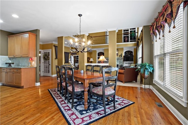 dining room featuring baseboards, visible vents, light wood finished floors, and an inviting chandelier