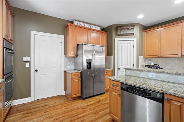 kitchen with stainless steel appliances, light stone countertops, and light wood-style floors