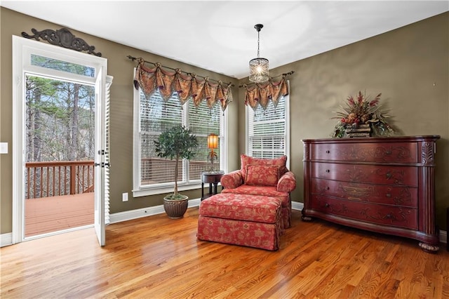 living area featuring baseboards, wood finished floors, and a notable chandelier