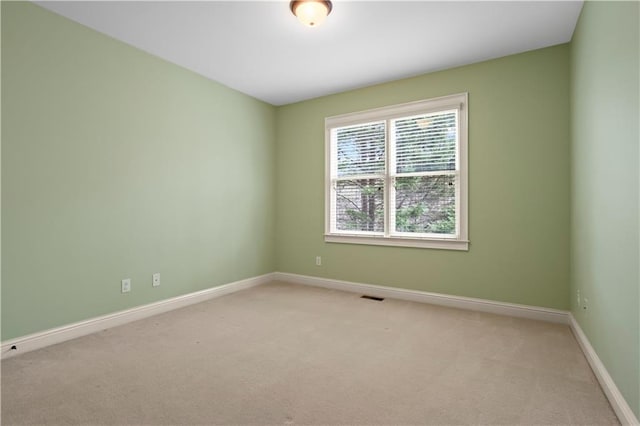 spare room featuring light carpet, visible vents, and baseboards