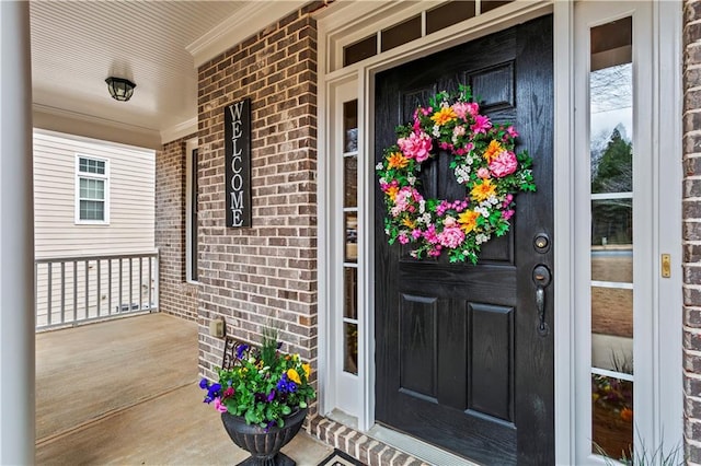 property entrance featuring covered porch and brick siding