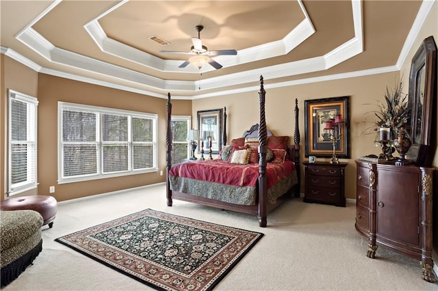 carpeted bedroom featuring ornamental molding, a tray ceiling, visible vents, and a ceiling fan