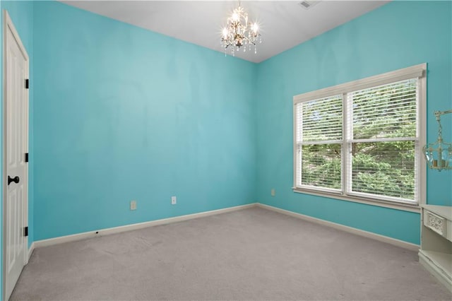 carpeted empty room featuring baseboards and a notable chandelier