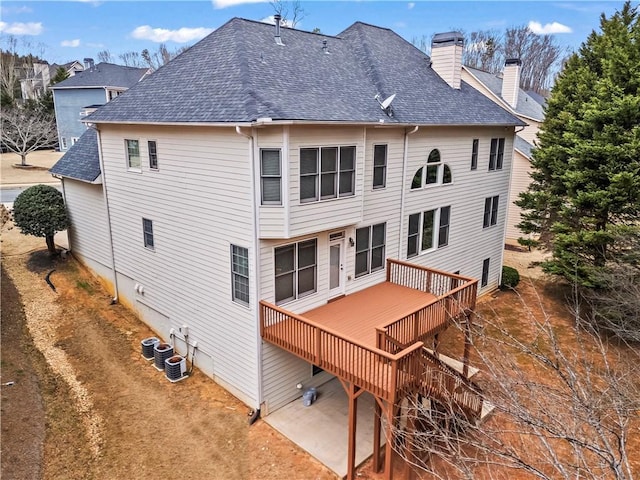 back of property featuring a shingled roof, a chimney, central AC unit, and a wooden deck