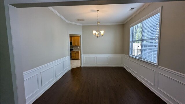 unfurnished dining area featuring a notable chandelier, crown molding, and dark hardwood / wood-style floors