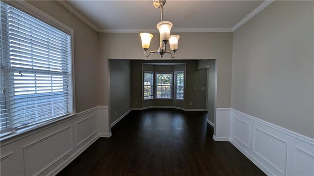 unfurnished dining area featuring dark wood-type flooring, an inviting chandelier, and crown molding