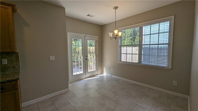 unfurnished dining area featuring light tile patterned flooring, a notable chandelier, and french doors