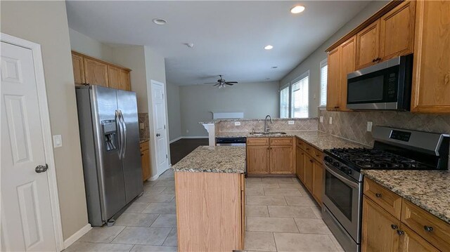 kitchen with a kitchen island, stainless steel appliances, light tile patterned floors, and backsplash