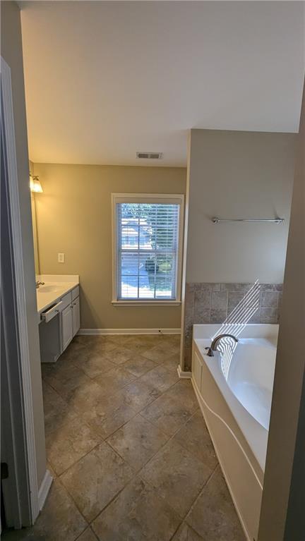 bathroom with a bathing tub, tile patterned flooring, and vanity