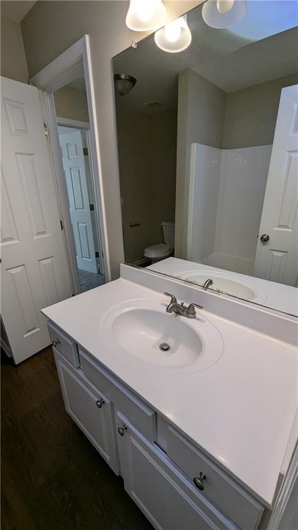 bathroom with toilet, vanity, and hardwood / wood-style flooring