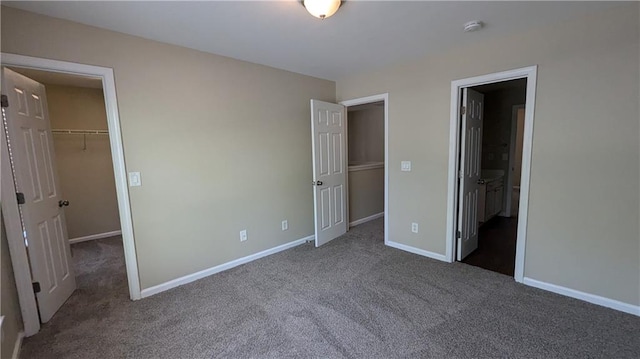 unfurnished bedroom with a closet, a spacious closet, and carpet floors