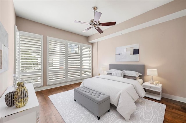 bedroom with ceiling fan, multiple windows, and dark hardwood / wood-style flooring