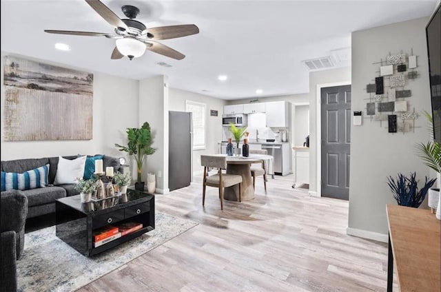 living room featuring light hardwood / wood-style flooring and ceiling fan