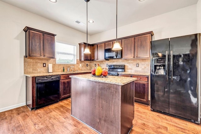 kitchen with sink, hanging light fixtures, dark brown cabinets, a center island, and black appliances