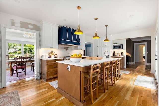 711 Greenview Ave NE, Atlanta, GA 30305 - kitchen with stainless steel microwave, wall chimney exhaust hood, light wood finished floors, tasteful backsplash, and white cabinetry