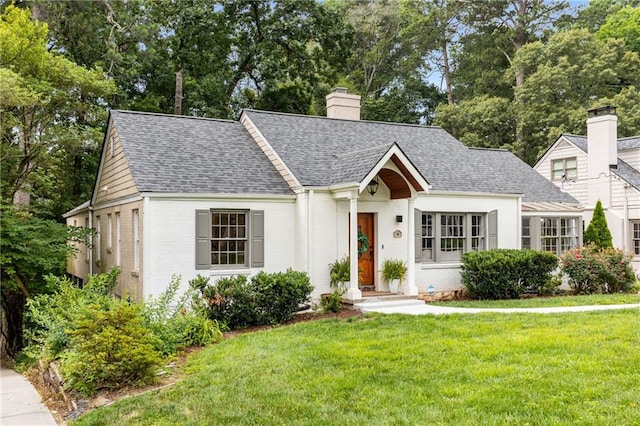711 Greenview Ave NE, Atlanta, GA 30305 - view of front of home featuring a front yard, roof with shingles, a chimney, brick siding, and view of scattered trees