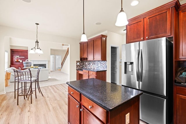 kitchen with decorative backsplash, stainless steel fridge, a kitchen island, and pendant lighting