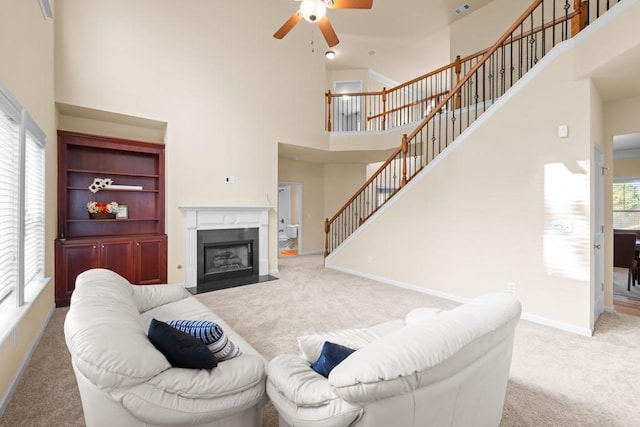 living room with carpet flooring, ceiling fan, a healthy amount of sunlight, and a high ceiling