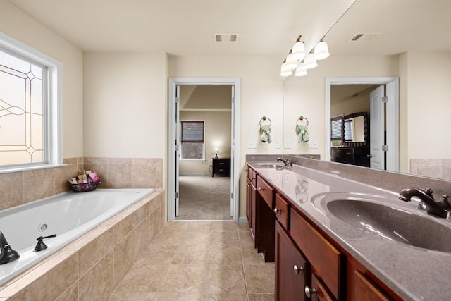 bathroom featuring tiled tub and vanity