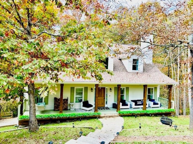 view of front of house with a front yard and an outdoor living space with a fire pit