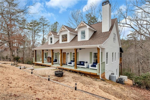 cape cod home featuring covered porch, central air condition unit, and an outdoor fire pit