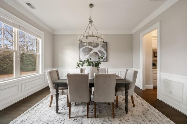 dining area with crown molding, dark wood-type flooring, and a chandelier