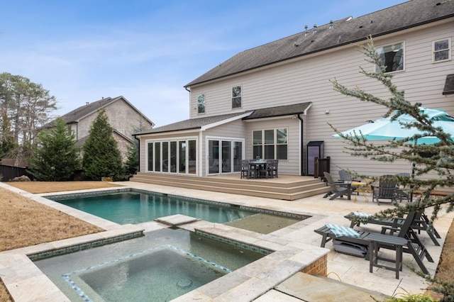 rear view of house featuring a swimming pool with hot tub and a patio