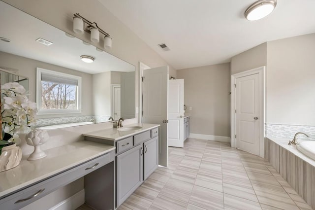 bathroom featuring vanity, tiled bath, and tile patterned flooring