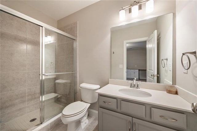 bathroom featuring vanity, tile patterned flooring, a shower with door, and toilet