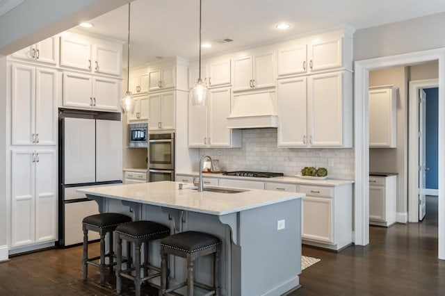 kitchen featuring pendant lighting, white cabinetry, sink, a kitchen island with sink, and stainless steel appliances