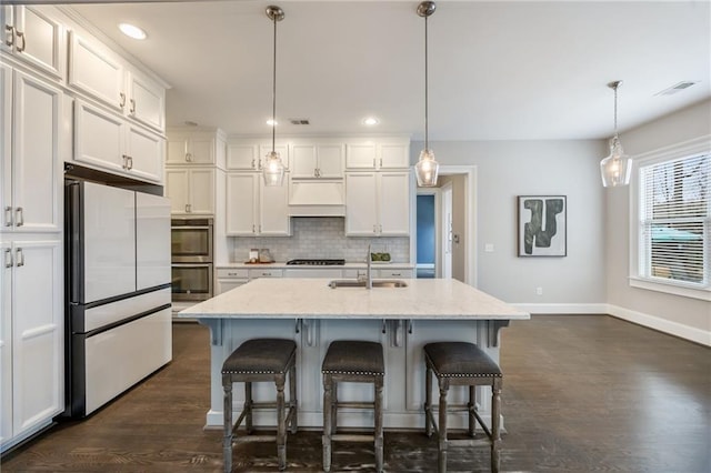 kitchen with pendant lighting, sink, a kitchen island with sink, and white refrigerator