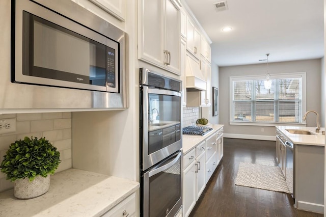 kitchen featuring sink, hanging light fixtures, stainless steel appliances, decorative backsplash, and white cabinets