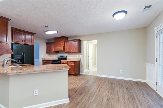 1731 Silverchase SW, Marietta, GA 30008 - kitchen featuring stainless steel range with electric stovetop, visible vents, premium range hood, a sink, and black refrigerator with ice dispenser