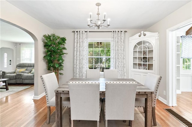 1359 Scott Blvd, Decatur, GA 30030 - dining area featuring a chandelier, light wood-type flooring, arched walkways, and plenty of natural light