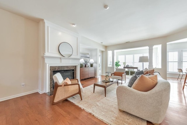 living room with a premium fireplace, baseboards, and light wood-style flooring