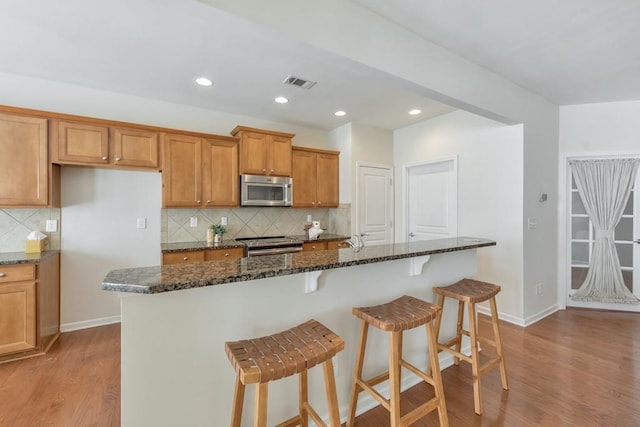 kitchen with stainless steel appliances, baseboards, visible vents, and wood finished floors