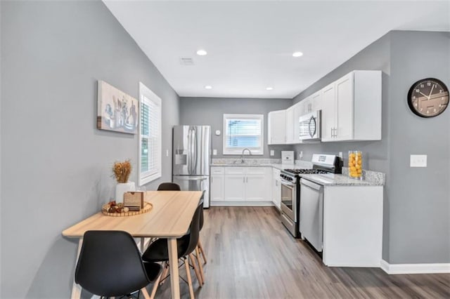 kitchen with white cabinetry, appliances with stainless steel finishes, hardwood / wood-style floors, and sink