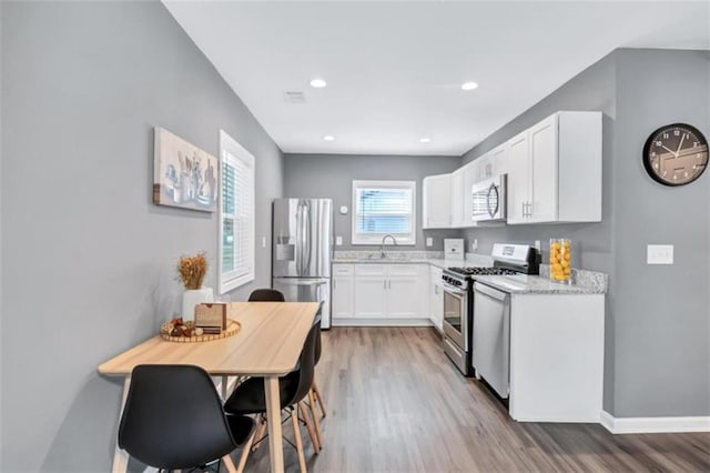 kitchen featuring a sink, light wood-type flooring, appliances with stainless steel finishes, recessed lighting, and white cabinetry