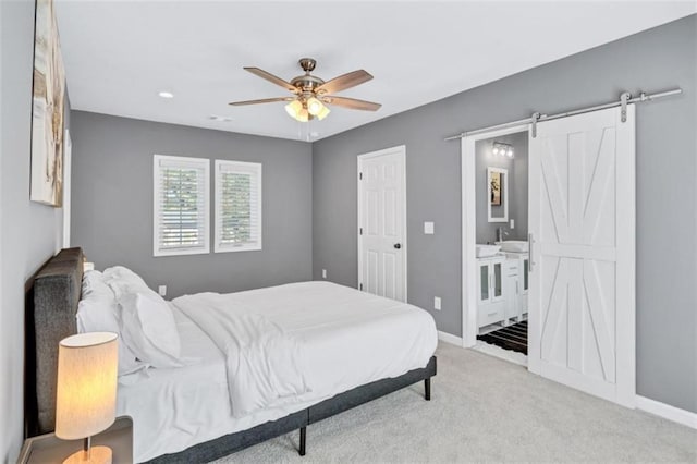 carpeted bedroom with connected bathroom, ceiling fan, and a barn door