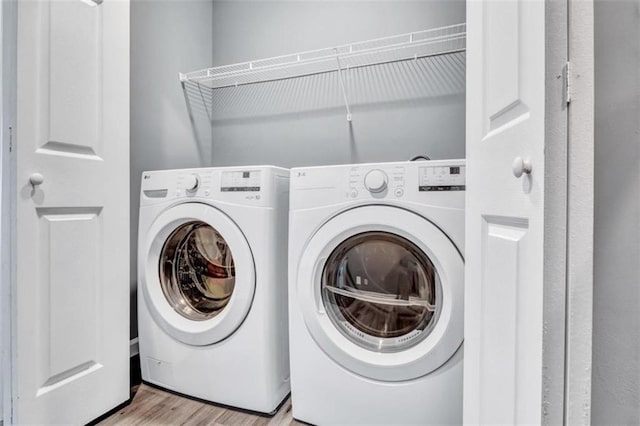 laundry area featuring wood finished floors, washer and dryer, and laundry area