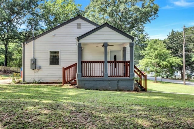 rear view of house featuring ceiling fan, stairway, and a lawn