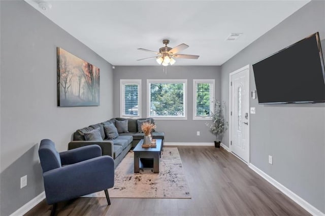 living area with visible vents, ceiling fan, baseboards, and wood finished floors