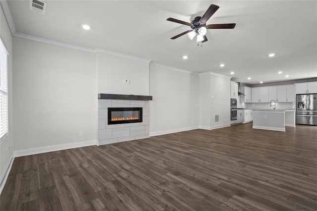 3382 Monarch Ave, Duluth, GA 30096 - unfurnished living room with crown molding, ceiling fan, dark wood-style flooring, recessed lighting, and a tiled fireplace